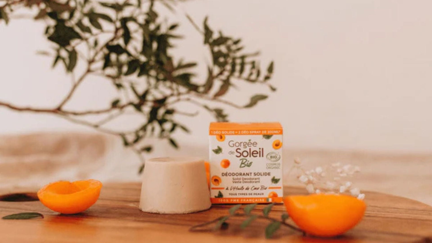 Déodorant solide bio "Gorgée de Soleil" à l'abricot sur une table en bois, avec des éléments naturels en arrière-plan – cosmétique naturel pour routine beauté bio.